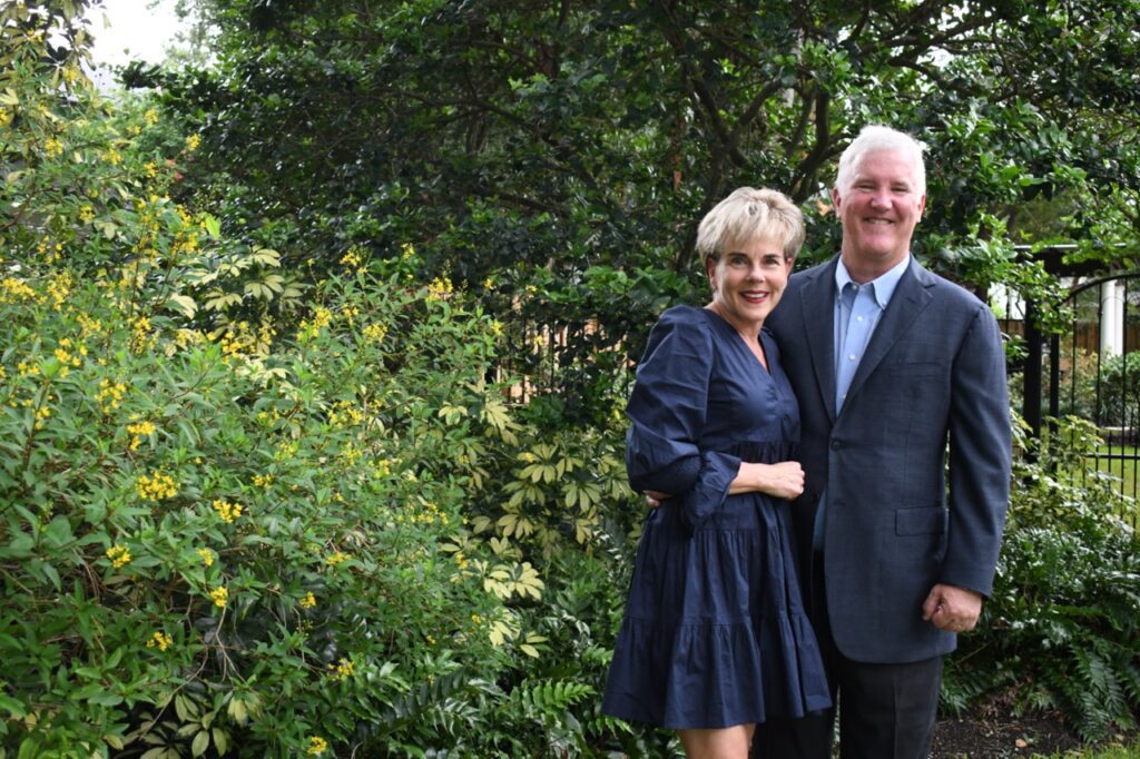 Image of Anne and John Koch standing in front of a foliage background